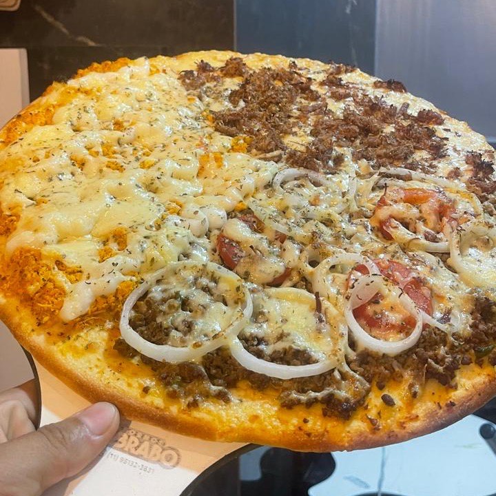 Pizza repartida em bolonhesa, frango com catupiry e sertaneja, com anel de cebola e rodela de tomate por cima